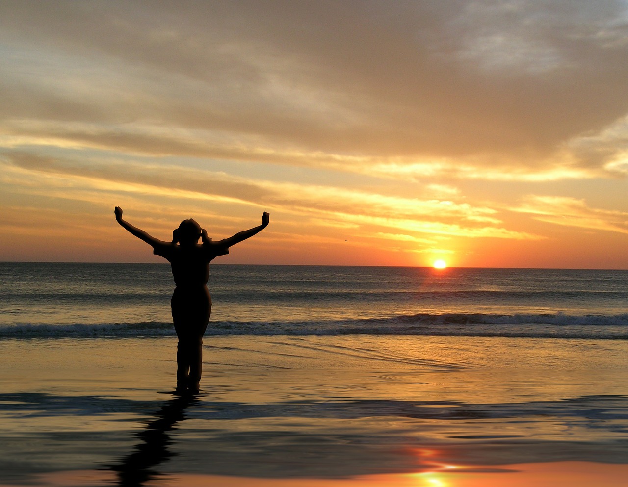 image of girl with outstretched arms looking at sunset